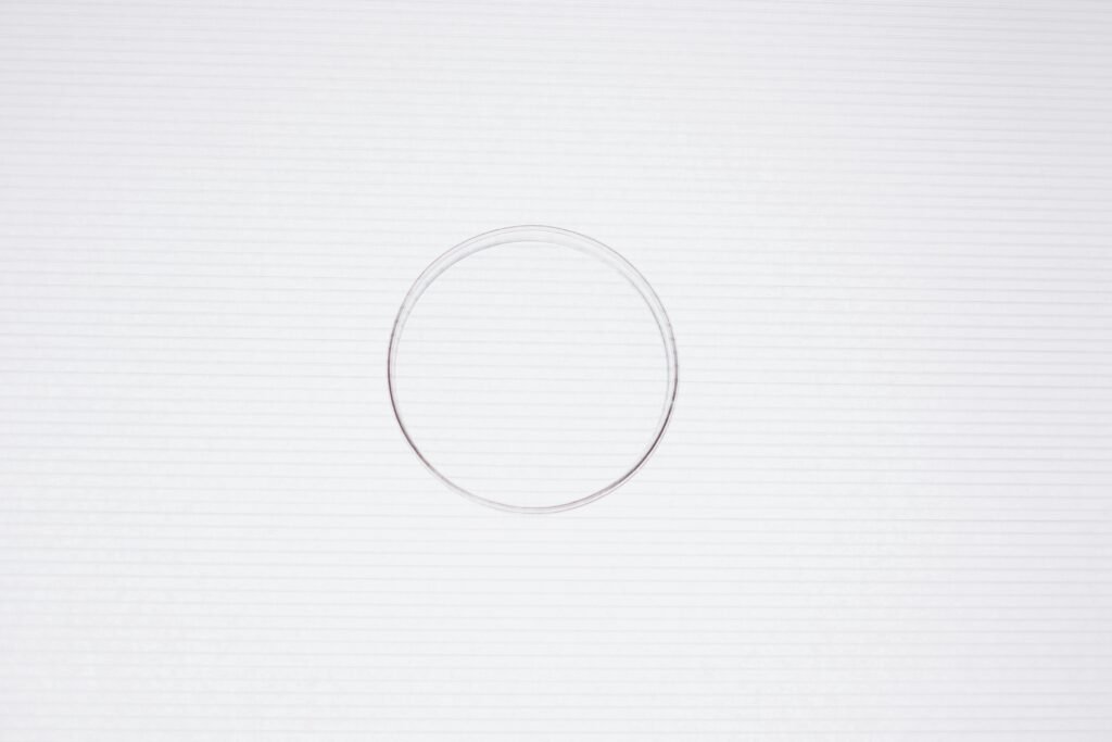Clear petri dish placed on a white textured background, viewed from above.